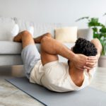 Fit young Arab guy exercising abs muscles on yoga mat at home. Domestic fitness concept