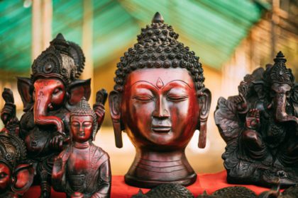 Goa, India. Traditional Store With Statues Different Colors And Sizes. Statues Of Buddha Head And