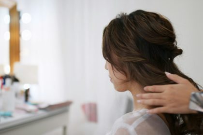 Hairdresser making hairstyle on bride in beauty salon