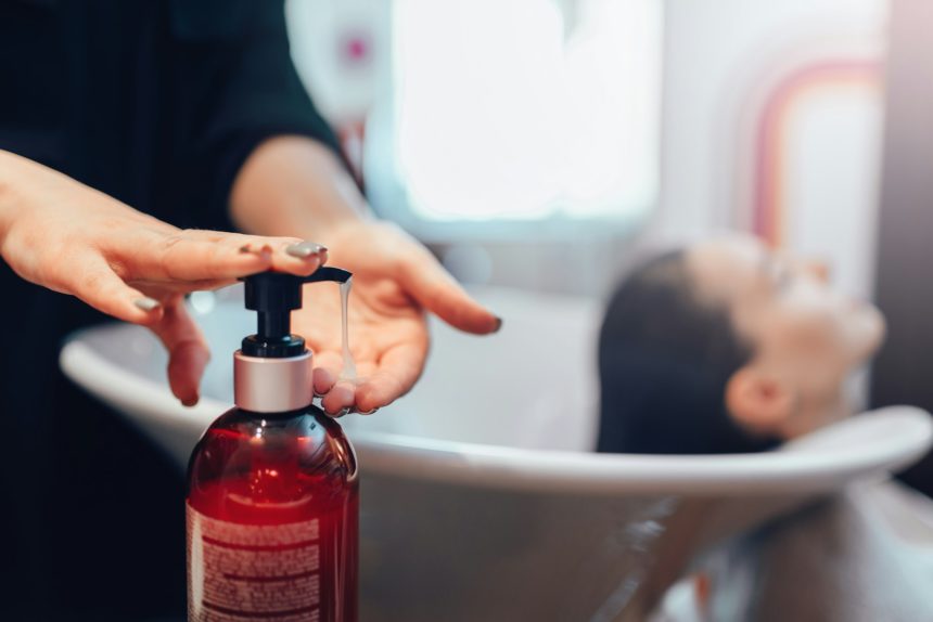 Hairdresser washes customer hair with shampoo