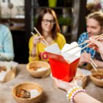 Holding a box with asian food indoors