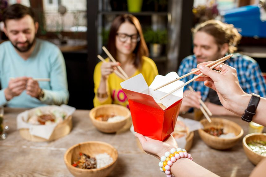 Holding a box with asian food indoors